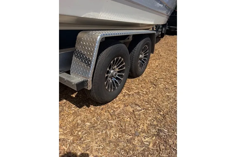 Slide: The Image of Trailer wheels of 2026 Robalo R270 Center Console on wood chips. - 44