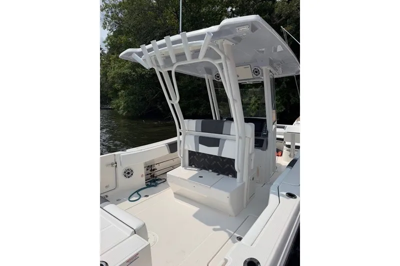 Slide: The Image of 2026 Robalo R270 Center Console boat with T-top and seating, docked near trees. - 23