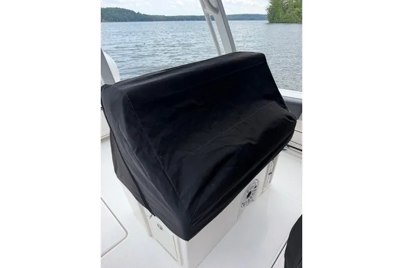 Slide: The Image of 2026 Robalo R270 Center Console boat with black seat cover on a lake. - 7
