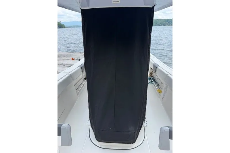 Slide: The Image of 2026 Robalo R270 Center Console boat interior with covered console, docked by a lake. - 8