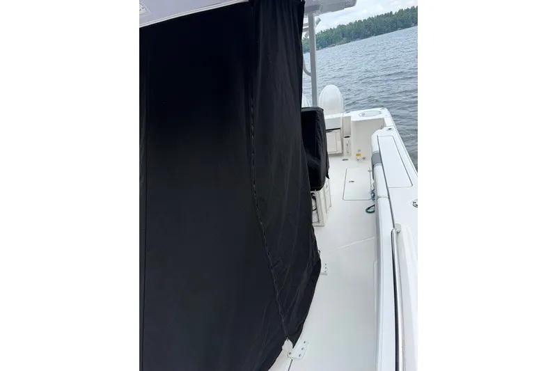 Slide: The Image of 2026 Robalo R270 Center Console boat with black cover on deck, near water. - 9