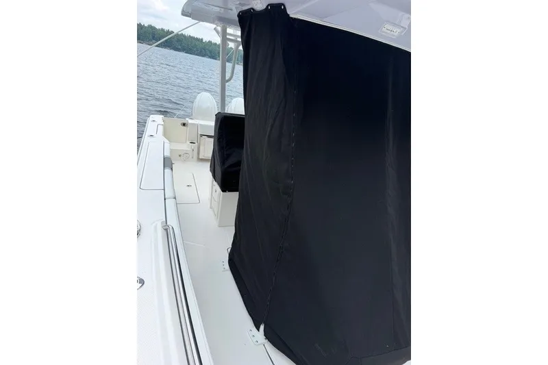 Slide: The Image of 2026 Robalo R270 Center Console boat with black cover on deck, near water. - 10