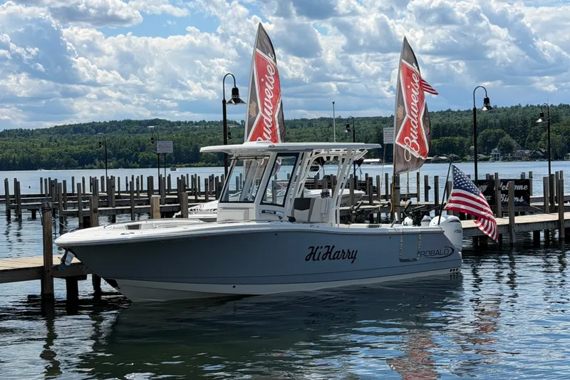 The Image of 2026 Robalo R270 Center Console boat docked with flags, scenic lake background. - 0