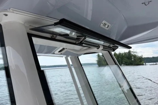 Slide: The Image of 2026 Robalo R270 Center Console boat windshield detail with scenic lake view. - 22