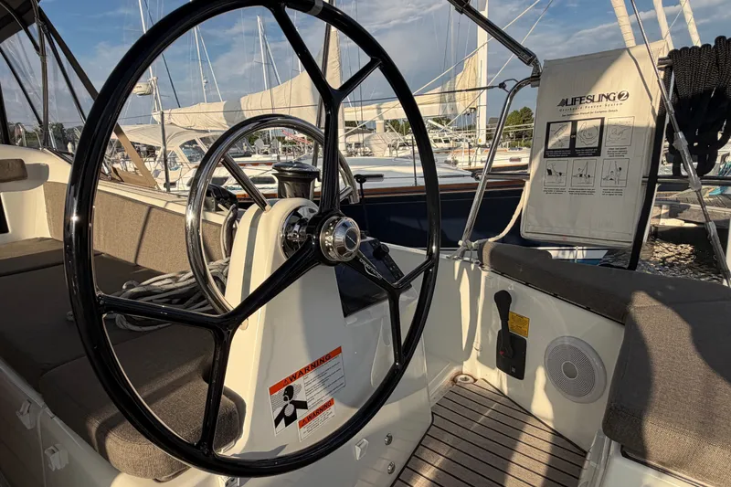 Slide: The Image of Steering wheel of 2024 Jeanneau Sun Odyssey 410 sailboat, docked with visible lifelines and seating. - 27