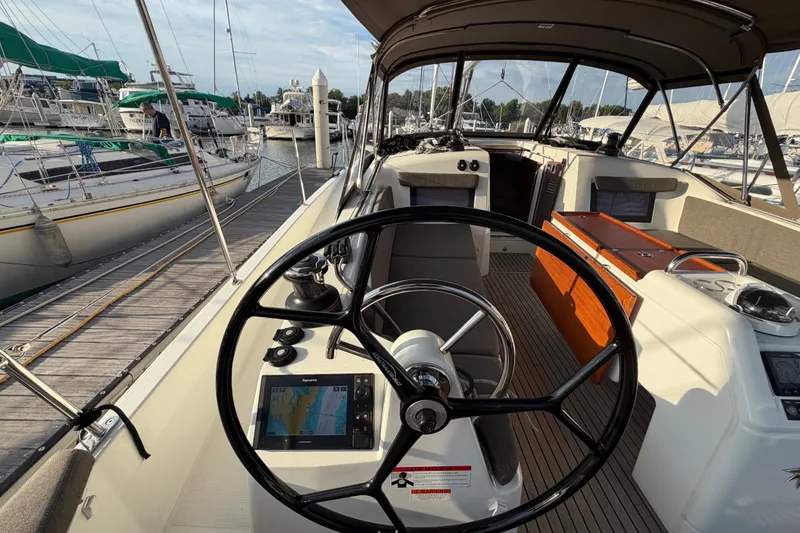 Slide: The Image of 2024 Jeanneau Sun Odyssey 410 cockpit with steering wheel and navigation display at marina. - 26