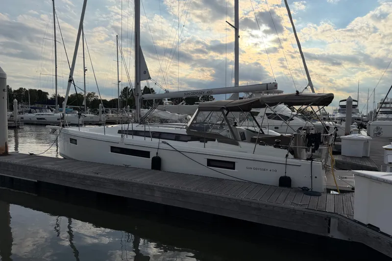 The Image of 2024 Jeanneau Sun Odyssey 410 sailboat docked at marina under cloudy sky. - 0