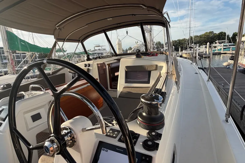 Slide: The Image of 2024 Jeanneau Sun Odyssey 410 sailboat cockpit with steering wheel and marina view. - 28