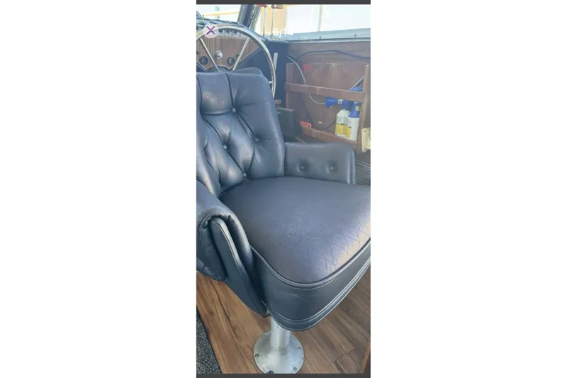Slide: The Image of Captain's chair in 1979 Tollycraft 40 Tri-Cabin Motor Yacht, featuring plush black upholstery. - 7