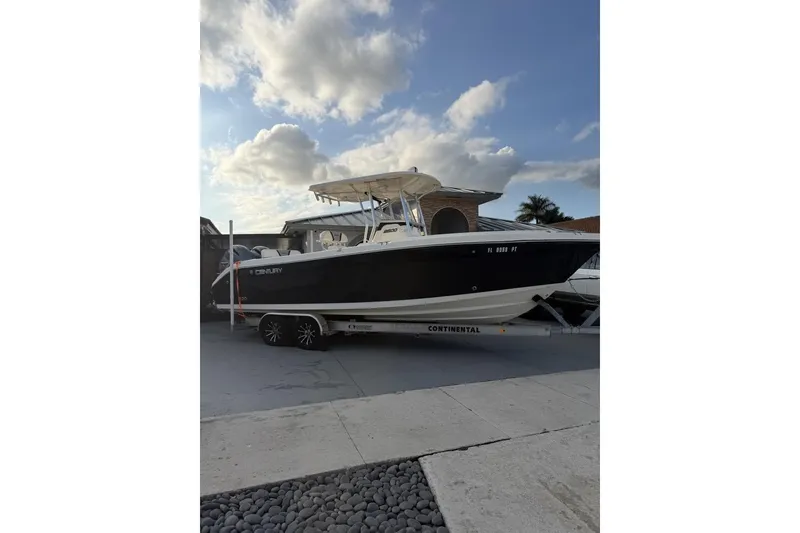 Slide: The Image of 2014 Century boat on trailer under cloudy sky, parked on driveway. - 1