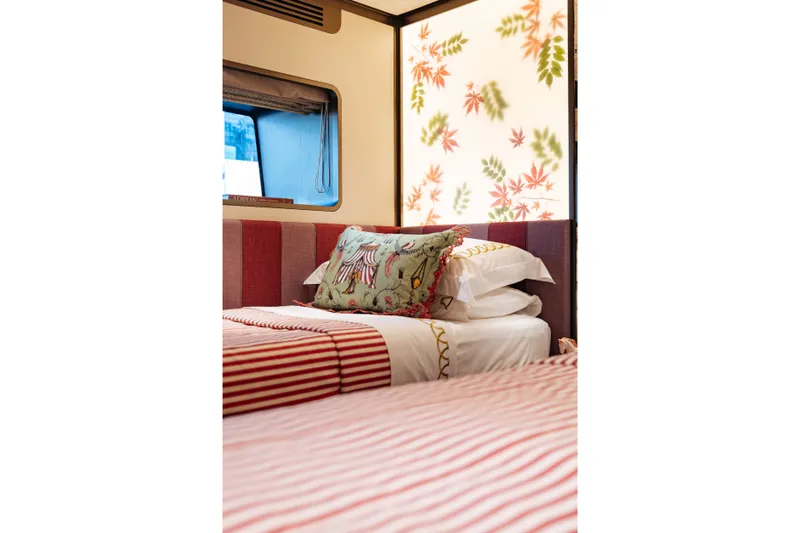Slide: The Image of Cabin with striped bed and decorative pillow, window, and illuminated panel with leaf pattern. - 21