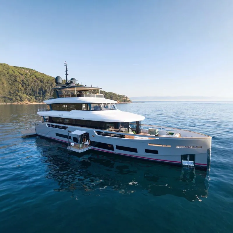 The Image of Sirena 118 yacht from 2027 on calm waters near a wooded coastline. - 0