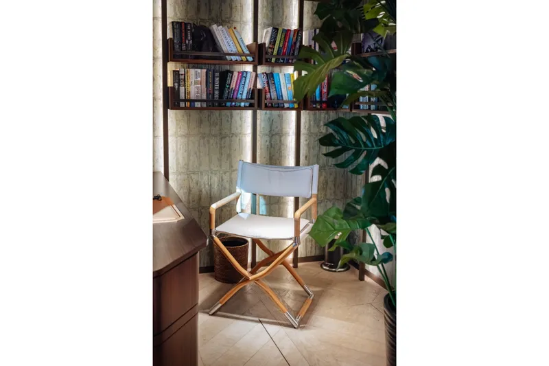 Slide: The Image of Cozy reading nook with director's chair, bookshelves, and lush plant in modern interior. Sirena 118, 2027. - 17