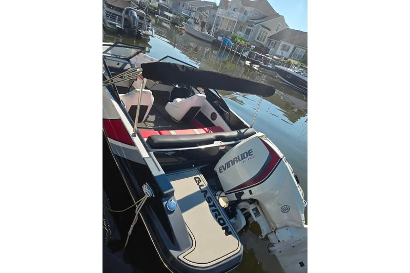 Slide: The Image of 2018 Glastron GTS 180 boat with Evinrude engine docked by waterfront homes. - 2
