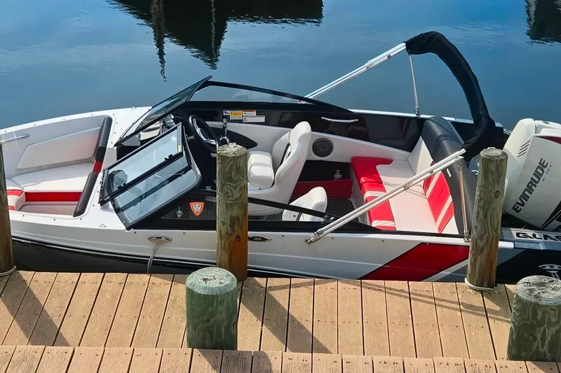 The Image of 2018 Glastron GTS 180 boat docked, featuring red and white interior, with Evinrude engine. - 0