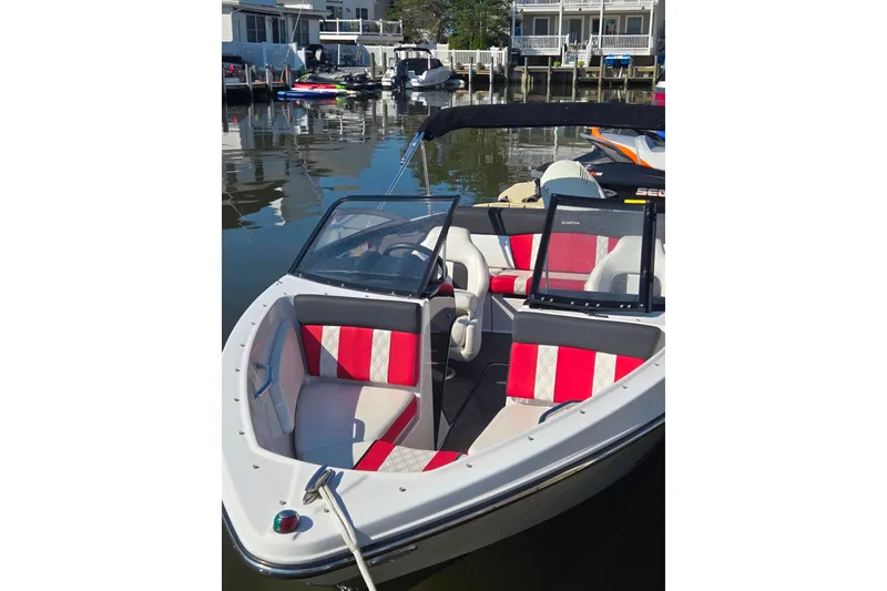 Slide: The Image of 2018 Glastron GTS 180 boat with red and white interior, docked in a marina. - 1