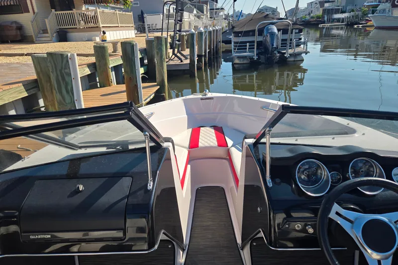 Slide: The Image of 2018 Glastron GTS 180 boat interior with dashboard and steering wheel, docked by waterfront homes. - 4