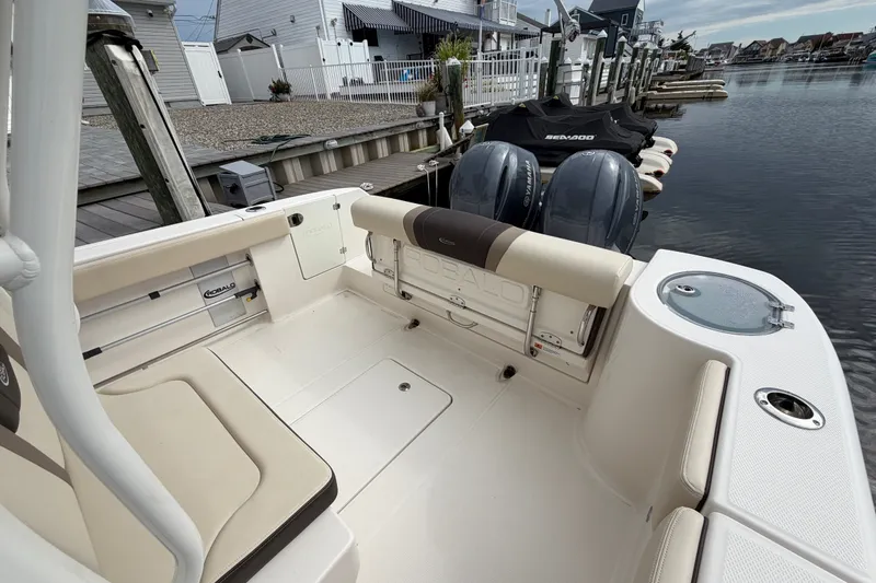 Slide: The Image of 2020 Robalo R272 Center Console boat interior with twin engines docked by waterfront homes. - 27