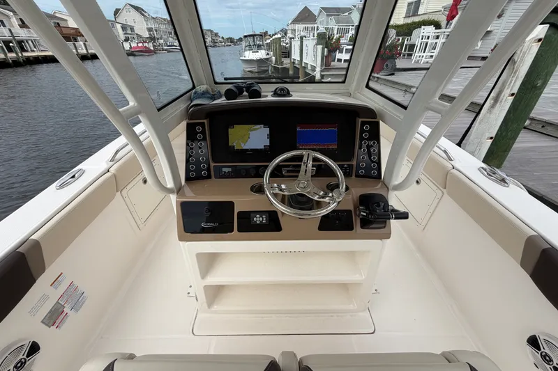 Slide: The Image of 2020 Robalo R272 Center Console boat helm with navigation screens and steering wheel. - 37