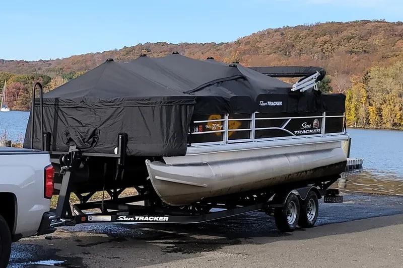 Slide: The Image of 2019 Sun Tracker Fishin' Barge 20 DLX on trailer by a scenic lake. - 34