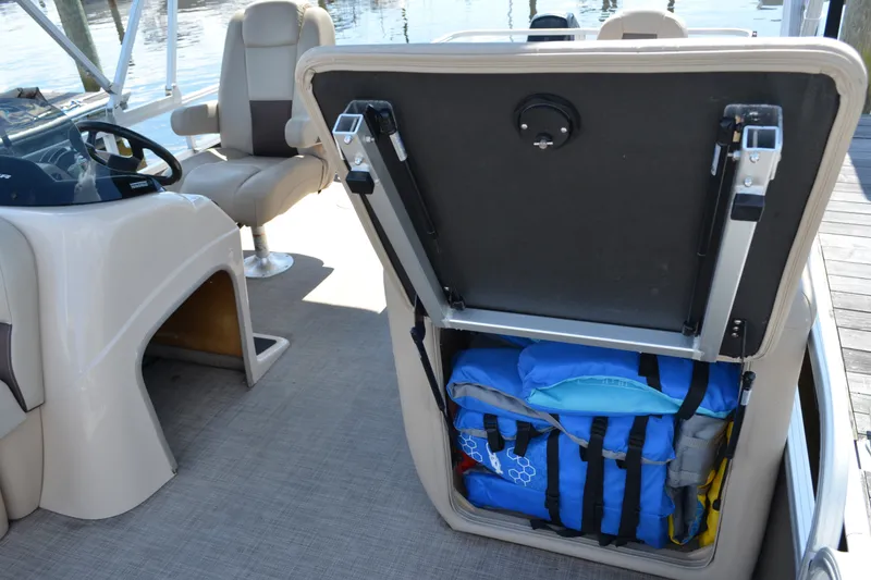 Slide: The Image of 2019 Sun Tracker Fishin' Barge 20 DLX with open storage compartment and life jackets. - 15