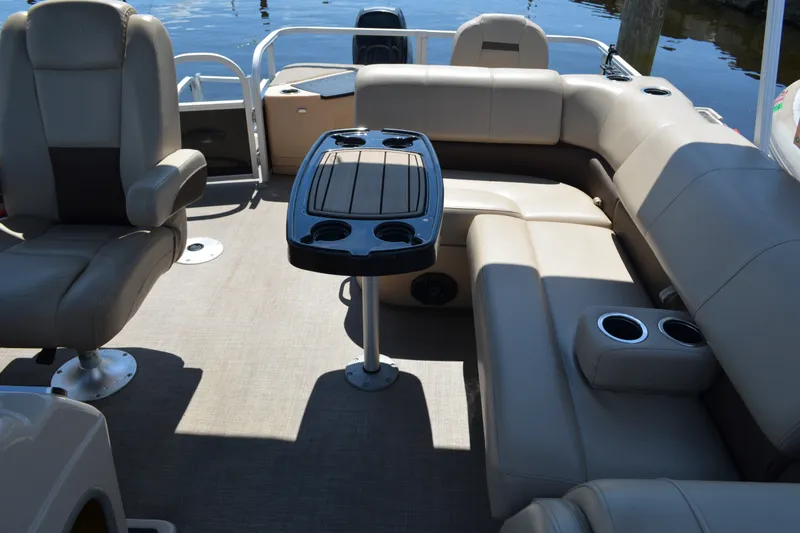 Slide: The Image of 2019 Sun Tracker Fishin' Barge 20 DLX interior with seating and table on water. - 16