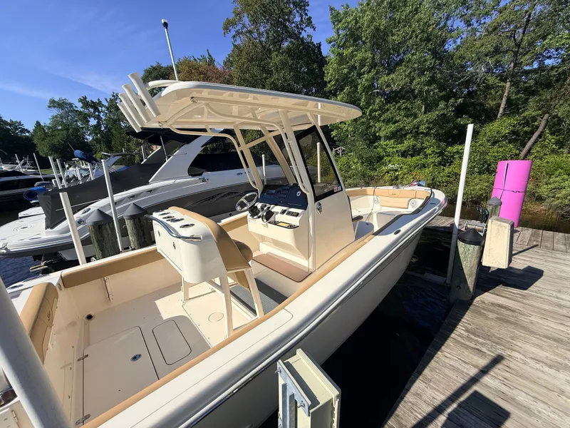 Slide: The Image of A 2018 Scout 235 XSF boat docked at a wooden pier, surrounded by trees and other boats. - 22