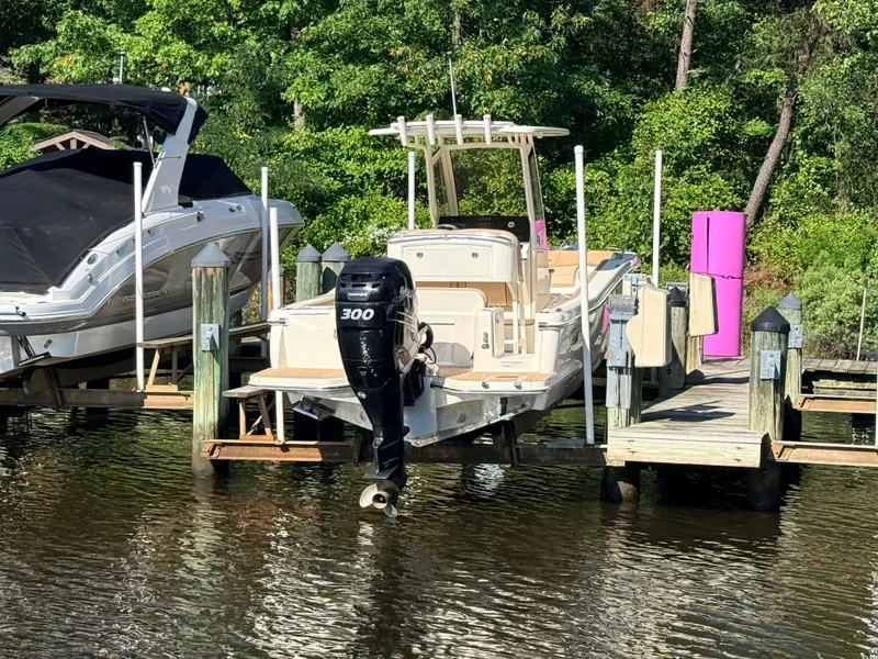 Slide: The Image of A 2018 Scout 235 XSF boat docked, surrounded by trees. - 24