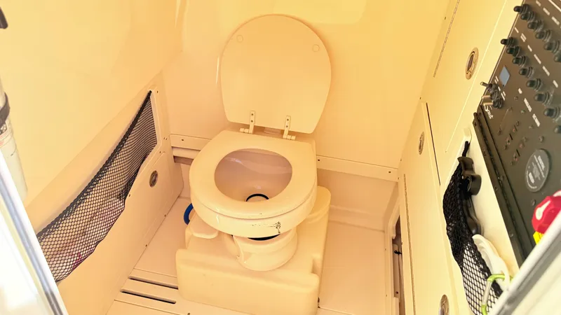 Slide: The Image of The image shows a toilet in a boat with beige walls and a control panel. - 20