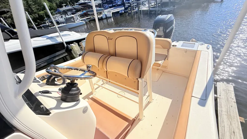 Slide: The Image of The image shows the cockpit of a 2018 Scout 235 XSF boat with beige seats and a helm. - 11