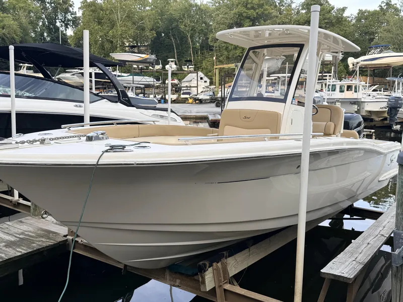 The Image of A 2018 Scout 235 XSF boat docked. It features an open deck and protective canopy. - 0
