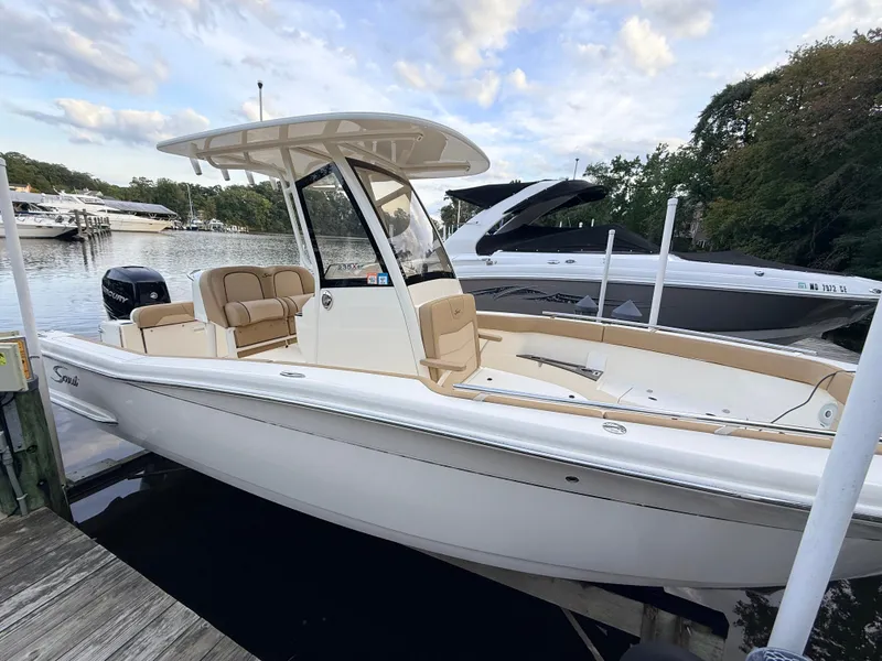 Slide: The Image of A 2018 Scout 235 XSF boat docked. It features a sleek design and a T-top. - 2