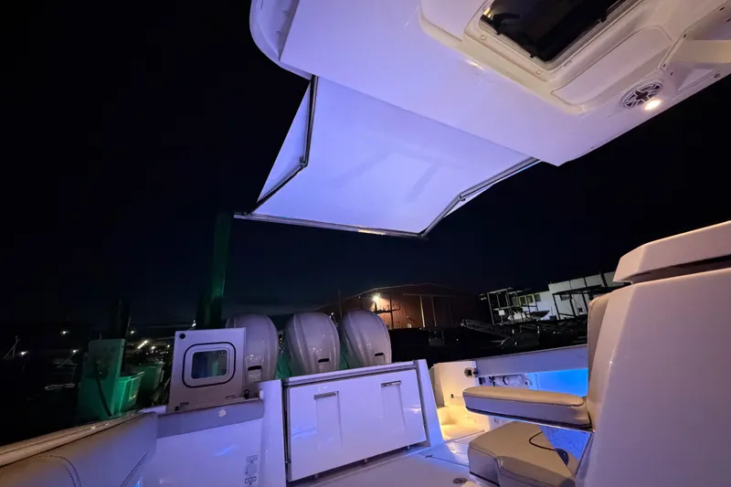 Slide: The Image of 2022 Pursuit S 378 Sport boat interior at night with illuminated seating and canopy. - 32
