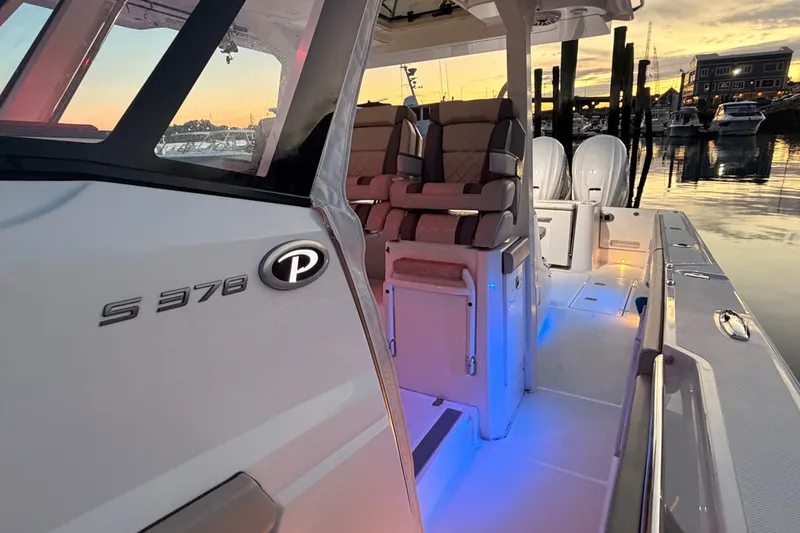 Slide: The Image of 2022 Pursuit S 378 Sport boat interior at sunset, featuring illuminated seating and controls. - 14