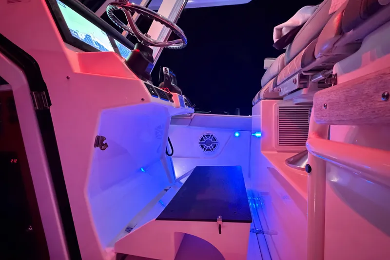 Slide: The Image of 2022 Pursuit S 378 Sport boat interior with illuminated dashboard and seating area at night. - 21