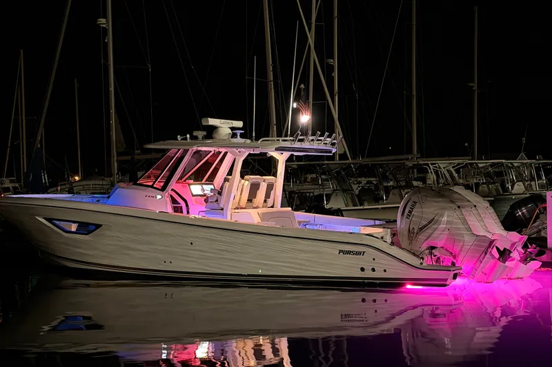Slide: The Image of 2022 Pursuit S 378 Sport boat illuminated at night with pink underwater lights. - 2