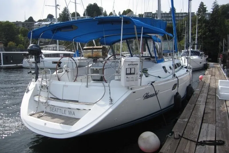 Slide: The Image of 2013 Jeanneau Sun Odyssey 44i sailboat docked, featuring blue canopy and Seattle registration. - 34