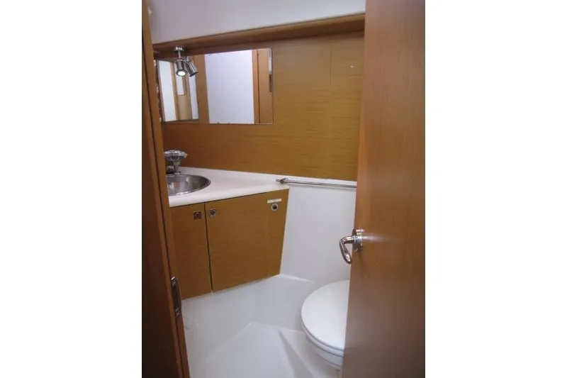 Slide: The Image of Bathroom interior of 2013 Jeanneau Sun Odyssey 44i yacht, featuring wooden cabinetry and stainless steel sink. - 13