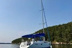 Slide: The Image of 2013 Jeanneau Sun Odyssey 44i sailboat on calm water near a forested shoreline. - 27
