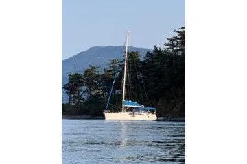 Slide: The Image of 2013 Jeanneau Sun Odyssey 44i sailboat on calm water near forested shoreline. - 28