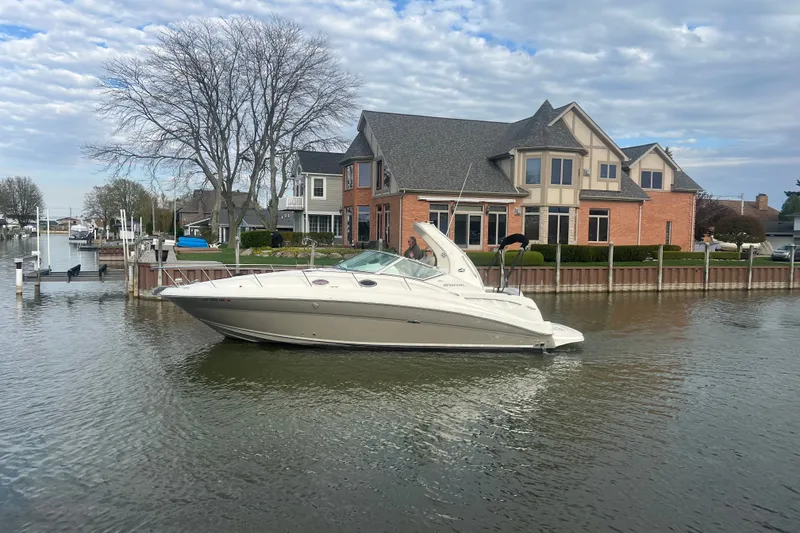 Slide: The Image of 2007 Sea Ray Sundancer 320 cruising near waterfront home under cloudy sky. - 2