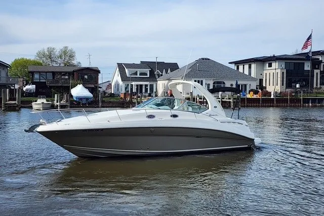 Slide: The Image of 2007 Sea Ray Sundancer 320 cruising on a calm waterfront near modern homes. - 57