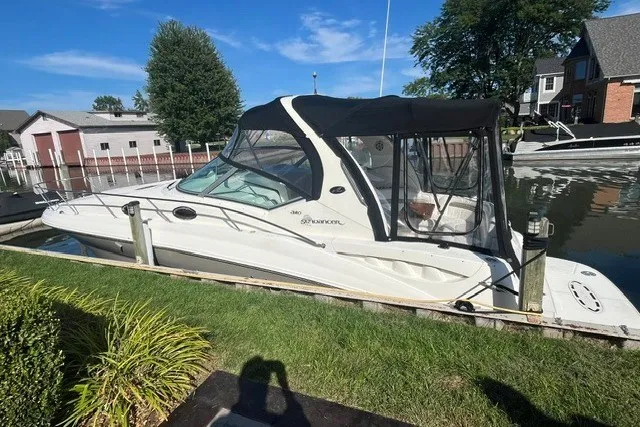 Slide: The Image of 2007 Sea Ray Sundancer 320 docked by a canal, featuring a sleek design and black canopy. - 3