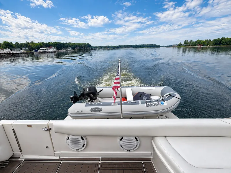 Slide: The Image of An inflatable boat with an outboard motor is towed behind a yacht on a calm lake. - 14