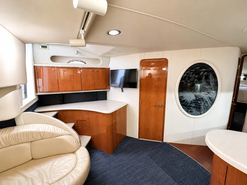 Slide: The Image of Interior of the 1999 Sea Ray 500 Sundancer with elegant wood furnishings and a round window. - 22