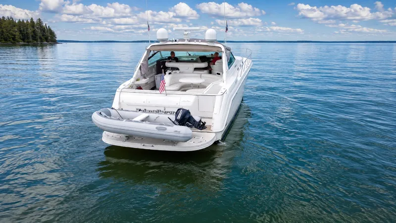 Slide: The Image of A 1999 Sea Ray 500 Sundancer on calm water with a dinghy at the stern. - 2