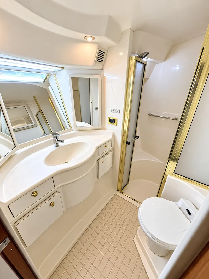 Slide: The Image of The image shows an elegant boat bathroom with white surfaces and gold accents. - 28