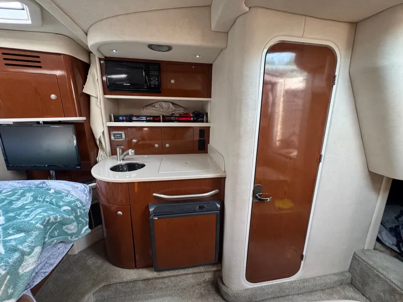 Slide: The Image of The cabin of a 2008 Sea Ray 290 Sundancer with a small kitchenette, microwave, and fridge. - 15