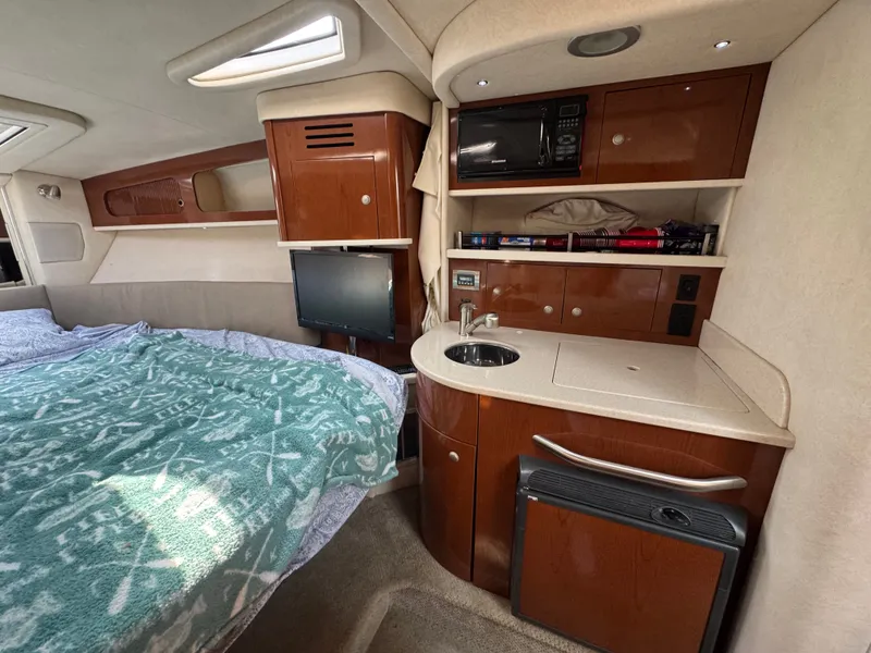 Slide: The Image of The cabin of the 2008 Sea Ray 290 Sundancer features a bed, kitchenette, and television. - 16