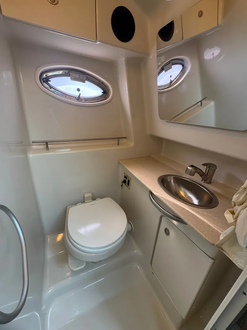 Slide: The Image of The image shows the bathroom of a 2008 Sea Ray 290 Sundancer with a toilet, sink, and mirror. - 19